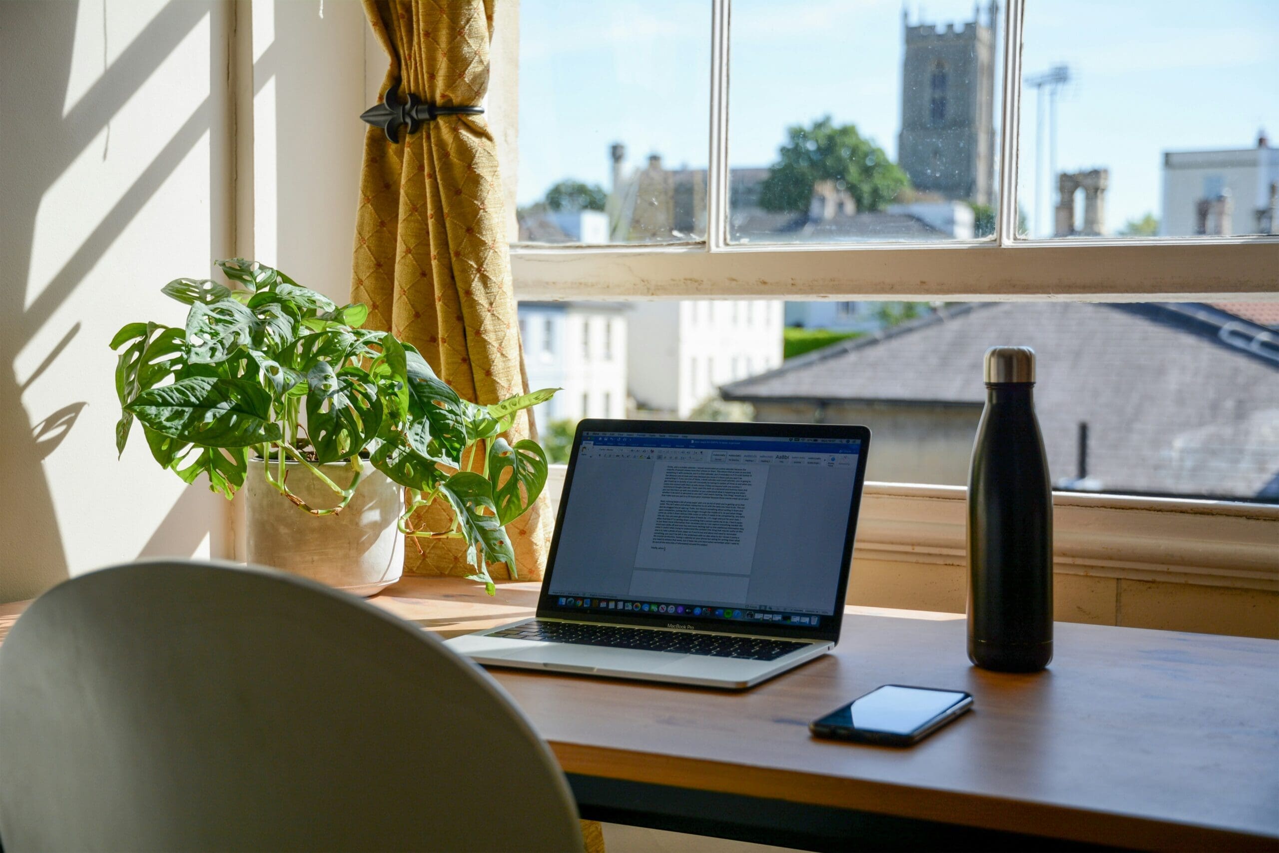 Laptop on a sunlit desk, representing reviewing real estate documents and home buying expenses
